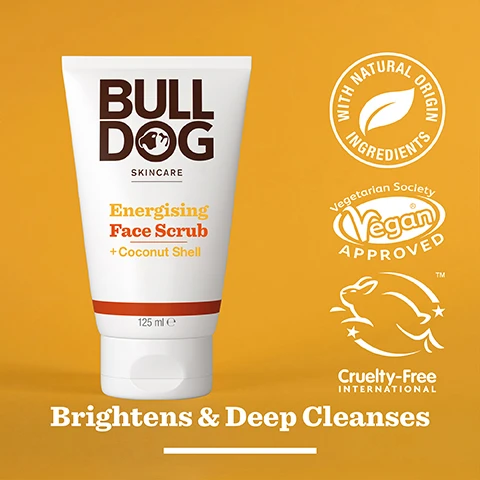 Image 2 - A white tube of Bulldog Skincare Energising Face Scrub with a brown logo and orange text on a yellow background, featuring icons for vegan approval, cruelty-free status, and the phrase Brightens & Deep Cleanses.
Image 3 - Two halved coconut shells are displayed, showing the white inner flesh, with text that reads 95% Natural Origin, Unlock the true potential of natural origin ingredients, Coconut Shell.
Image 4 - A person holds a tube of Bulldog Skincare Energising Face Scrub, with the cap open, and the visible text includes Dull & Tired Skin.
Image 5 - A tube of Bulldog Skincare Energising Face Scrub with a coconut shell formula prominently displayed, featuring a description of its natural ingredients and environmental sustainability, along with visible text stating Recycled Tube, 125 ml, and information about the tubes composition.
Image 6 - Three Bulldog skincare products on a bright orange background, including Energising Face Scrub, Energising Face Wash, and Energising Moisturiser, with additional text saying Revitalise Dull & Tired Skin.