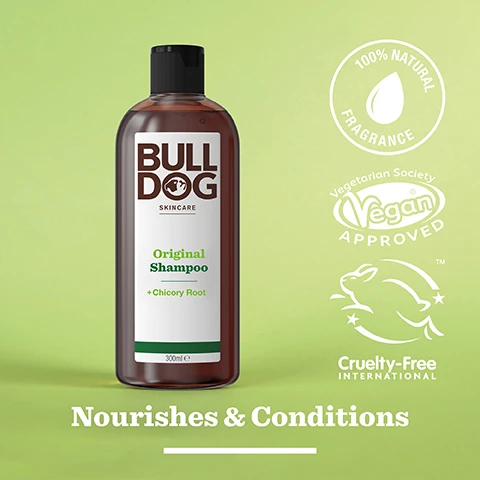 Image 2 - A brown bottle of Bulldog Original Shampoo with green accents is displayed on a light green background, featuring text that reads Bulldog skincare, Original Shampoo, +Chicory Root, 300ml, and the phrases Nourishes & Conditions, 100% Natural Fragrance, Vegan Approved, and Cruelty-Free International.
Image 3 - Dried pieces of chicory root scattered on a light marble surface with the text 100% Natural Fragrances and Chicory Root.
Image 4 - A person with a light brown skin tone is holding a bottle of Bull Dog Original Shampoo, tilting it to pour a small amount into their open palm, with the text Nourishes & Conditions visible below in a large font.
Image 5 - A hand holds a brown shampoo bottle labeled Bulldog Skincare Original Shampoo + Chicory Root, and there is a circular graphic indicating the bottle is made from 100% recycled PCR plastic.
Image 6 - Two bottles of Bulldog Skincare products are displayed on a tiled surface, with the left bottle labeled Original Shower Gel and the right bottle labeled Original Shampoo, both featuring green accents and additional text about their benefits; the text at the bottom reads Start the Day Right.