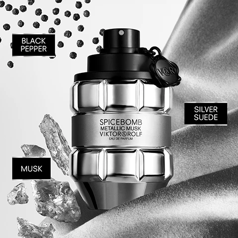 Image 1 - A metallic grenade-shaped perfume bottle with a black top stands surrounded by black peppercorns, silvery rock fragments, and silver draped fabric, with the visible text SPICEBOMB METALLIC MUSK VIKTOR&ROLF EAU DE PARFUM, BLACK PEPPER, MUSK, SILVER SUEDE. Image 2 - A silver grenade-shaped perfume bottle bursts with water splashes around it, featuring text that reads SPICEBOMB METALLIC MUSK, SPICEBOMB METALLIC MUSK VIKTOR & ROLF EAU DE PARFUM, and VIKTOR & ROLF. Image 3 - Two silver and black perfume bottles shaped like grenades are displayed side by side, with the larger bottle on the left and the smaller on the right, both featuring a VR tag and visible text SPICEBOMB METALLIC MUSK VIKTOR&ROLF EAU DE PARFUM, with sizes indicated below as 90 ML (3OZ) and 50 ML (1.7OZ). Image 4 - A black and white image features a shirtless, muscular man holding a grenade-shaped perfume bottle as another identical bottle splashes in water, with the text SPICEBOMB METALLIC MUSK VIKTOR & ROLF. Image 5 - The image shows five bomb-shaped Spicebomb Viktor & Rolf fragrance bottles, visually distinct and labeled with SPICEBOMB VIKTOR & ROLF, NIGHT VISION EAU DE TOILETTE, SPICEBOMB EAU DE TOILETTE, METALLIC MUSK EAU DE PARFUM, DARK LEATHER EAU DE PARFUM, and EXTREME EAU DE PARFUM INTENSE, further described by FRESH, SPICY, CAPTIVATING, ENIGMATIC, and INTENSE.